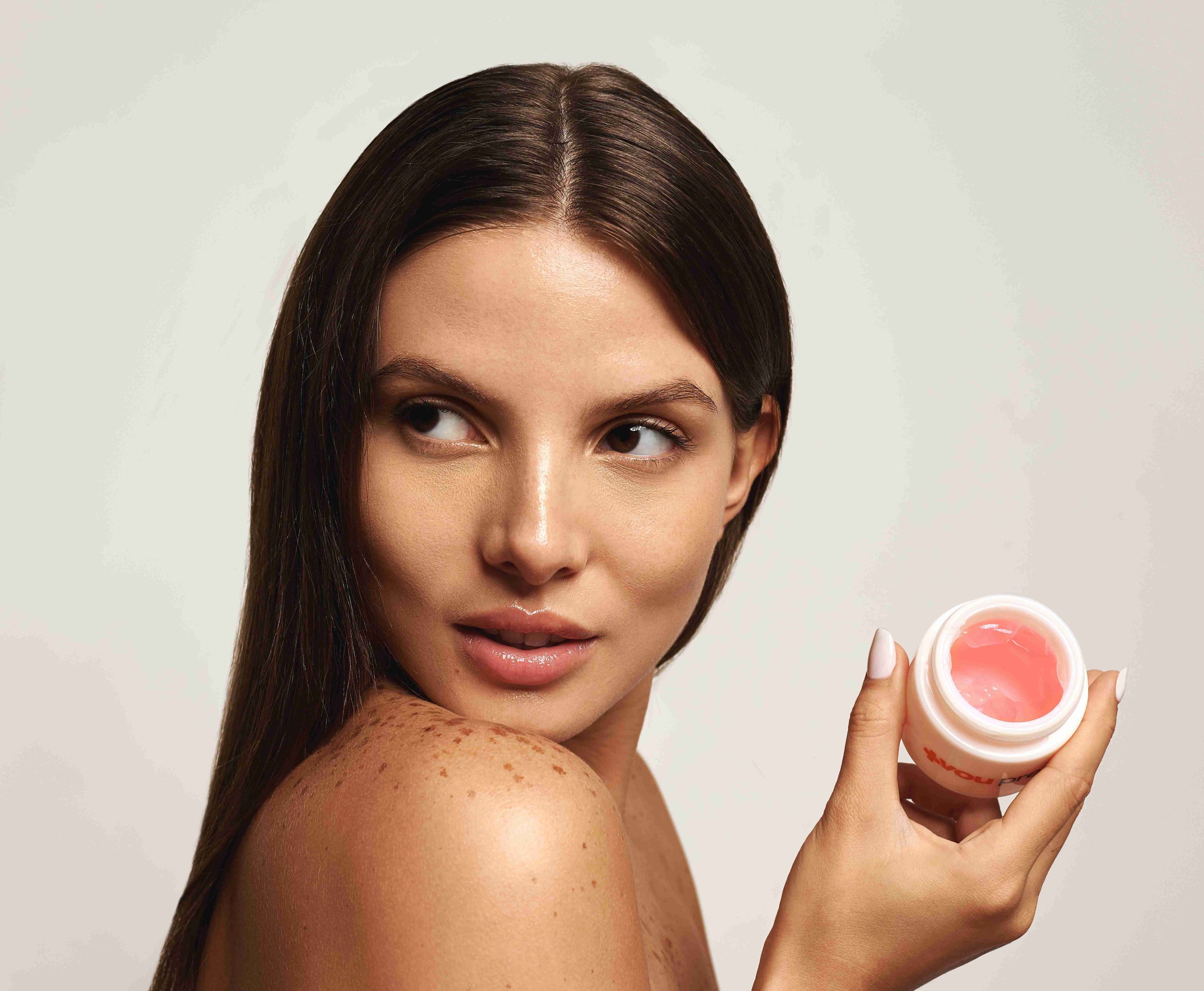 Woman holding an open jar of the Deep Renewal Facial Peel