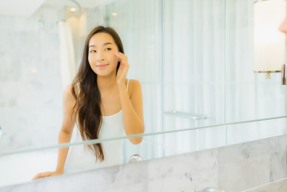 Woman looking at skin in mirror