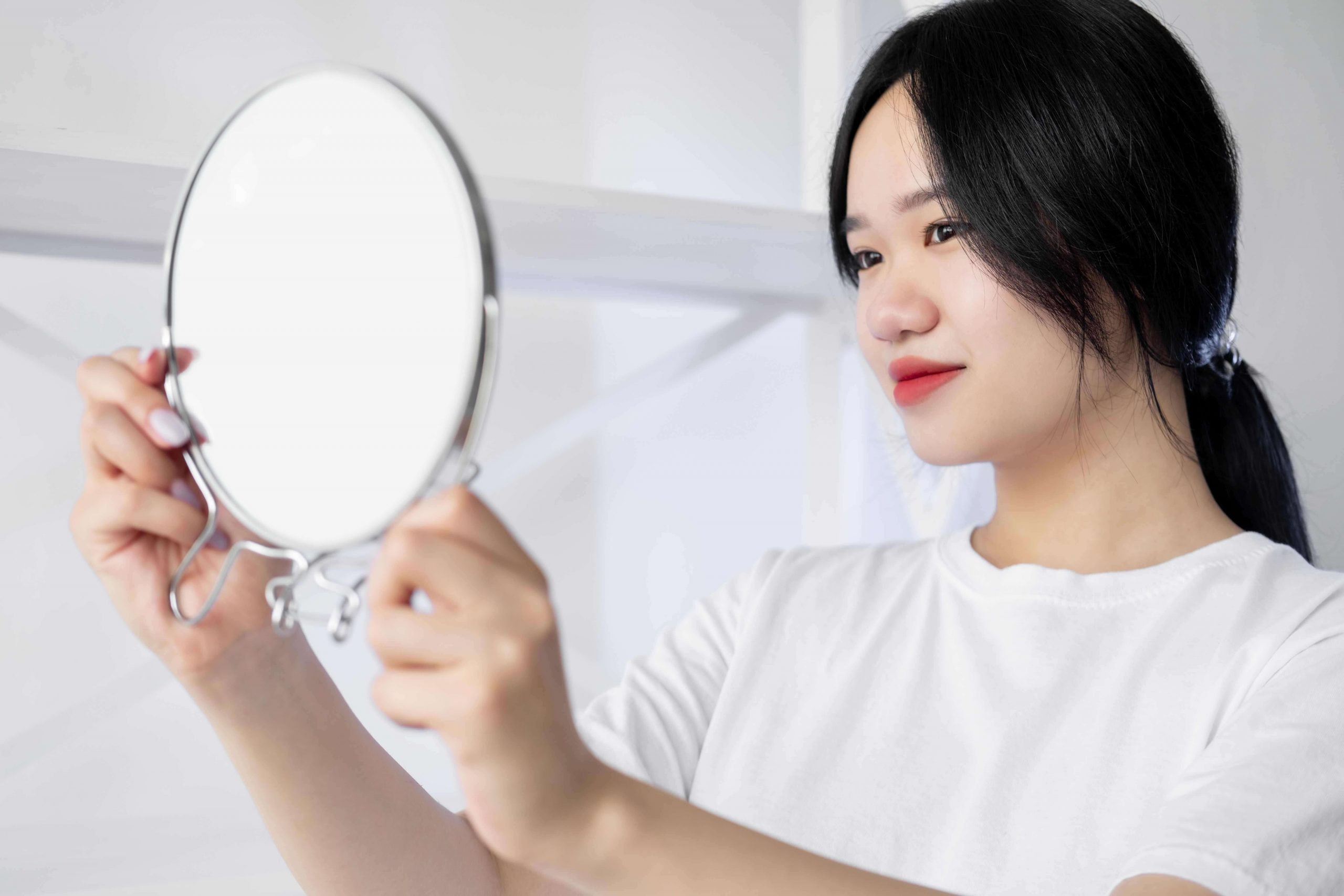 Woman looking in mirror after using eye cream