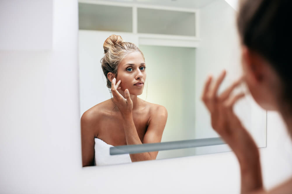 Woman looking at skin in mirror