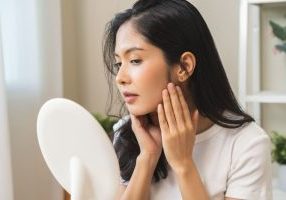 Woman looking at her dull skin in the mirror